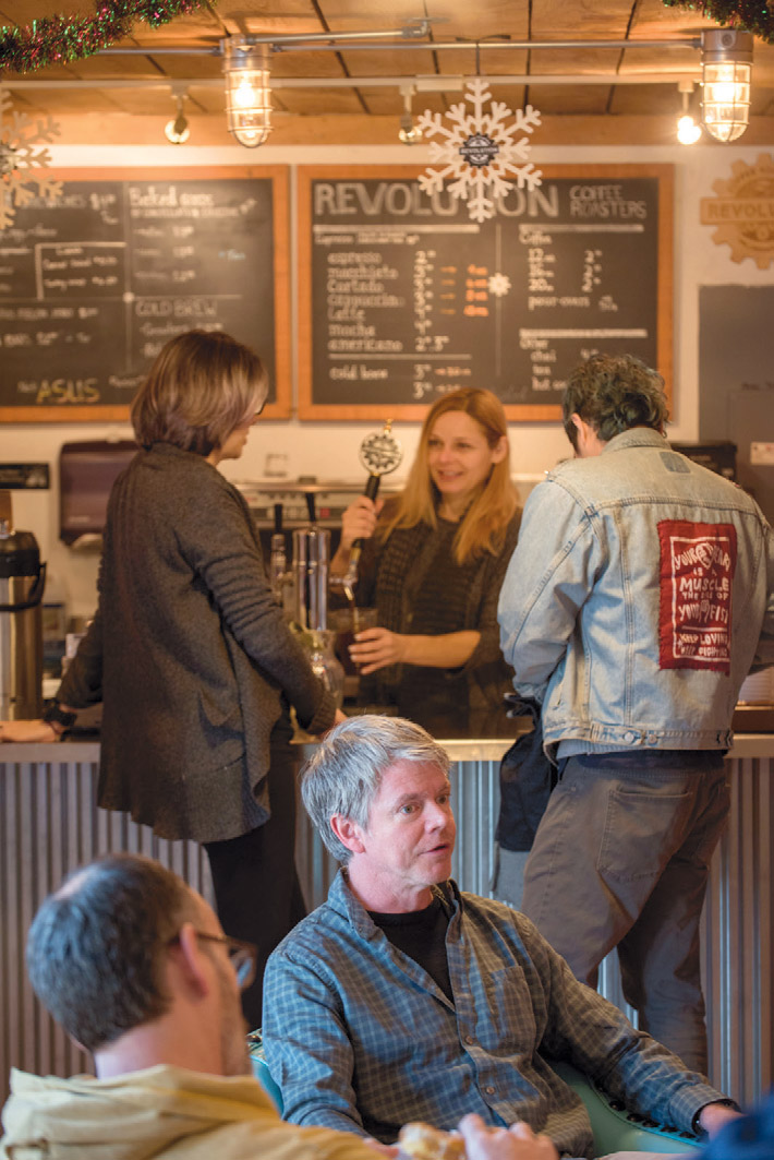 Steve McFadden (seated), co-owner of Revolution Coffee Roasters, chats with customers