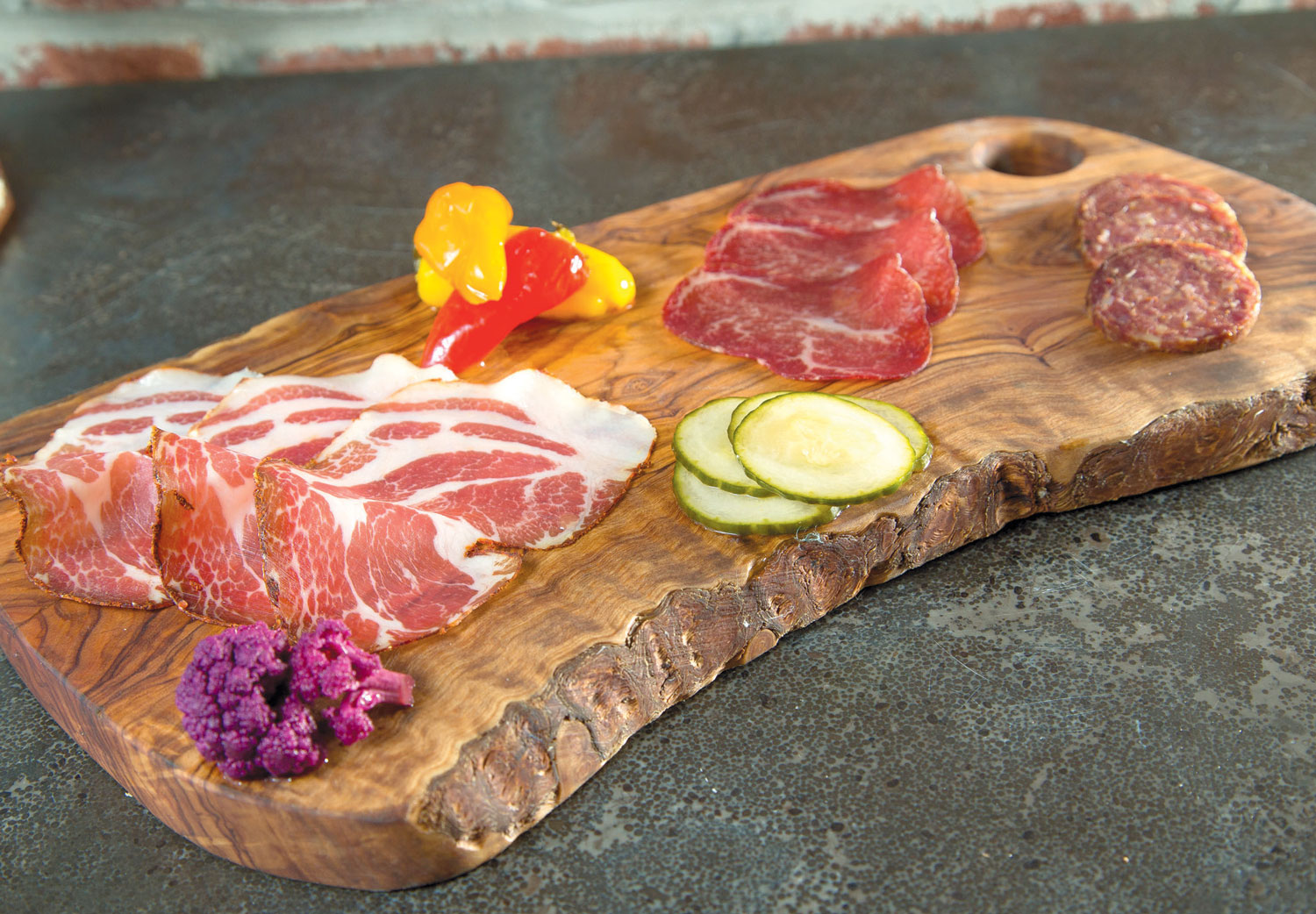 selection of salumi (cured meats) on a plank with vegetables