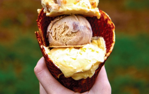 Multiple scoops of fresh churned ice cream in a waffle cone