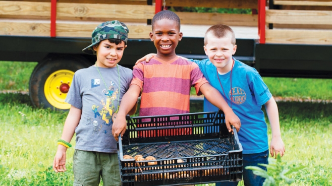 Adrian Lopez, 7, Ethan Davis, 7, and Anthony Salkauski, 8, carry freshly harvested potatoes at Gravity Hill Farm. 