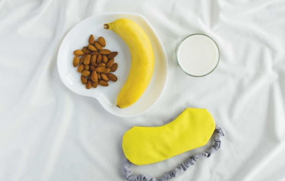 a banana and almonds on a plate next to a sleep mask