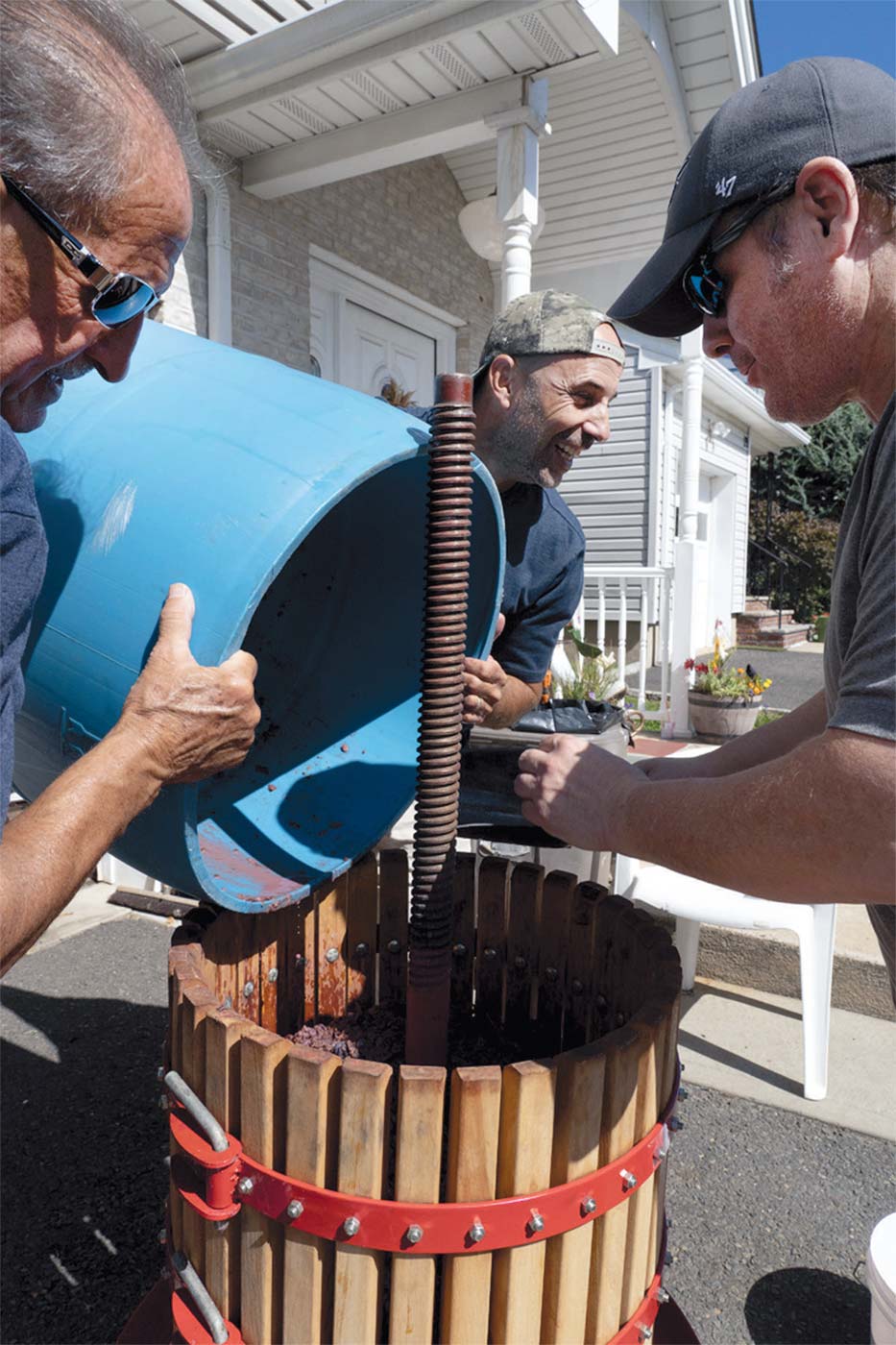 Lou’s son Joe Raio (c) begins the annual grape pressing with relatives Victor (l) and Joe Rajoppi (r).