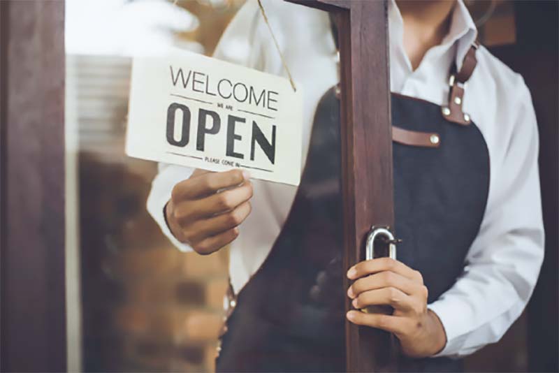 restaurant owner turning an open sign to closing
